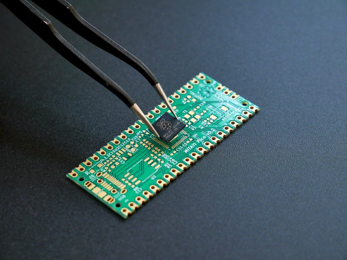 Pinzetta che posiziona un microchip su una scheda a circuito stampato